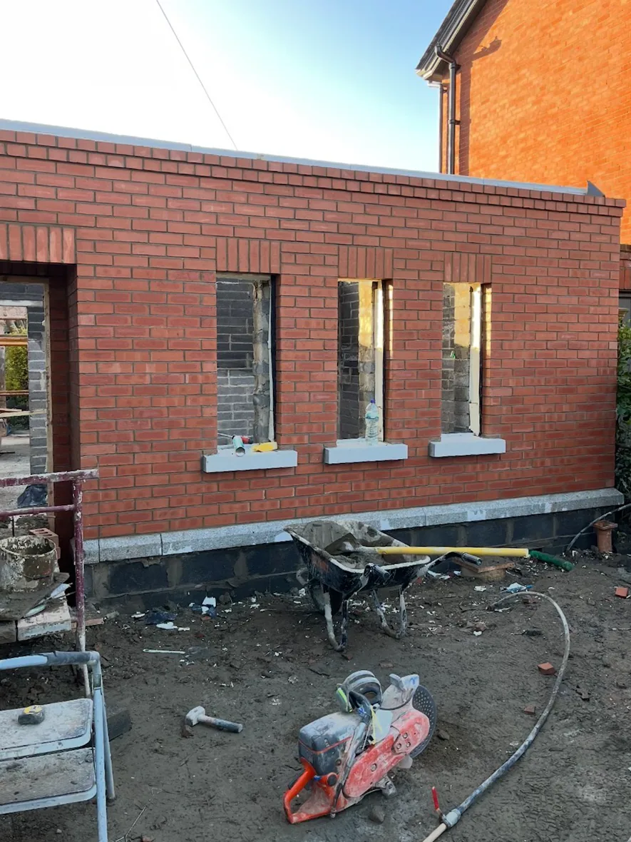 Red brick extension wall with soldier-course window heads and granite cills, under construction