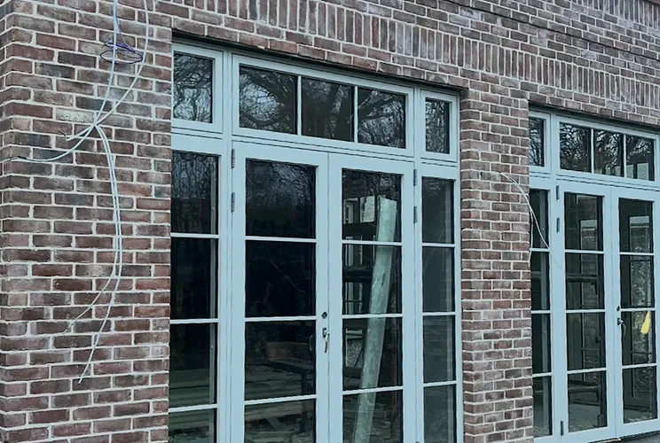 Single-storey red brick extension with pale glazed doors and a soldier-course parapet