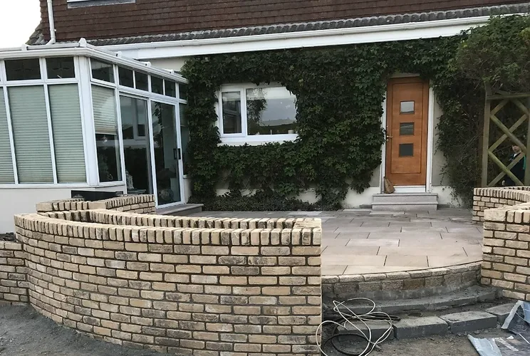 Curved buff brick garden wall with soldier-course coping enclosing a paved terrace